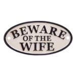 Humoristisk skylt i gjutjärn med texten BEWARE OF THE WIFE. En lekfull och dekorativ detalj som passar i hall, kök eller vid entrén.