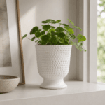 Blomkruka på fot i vitt stengods med dekorativ struktur och elegant form. Stilren kruka som passar fint med gröna växter och nordisk inredning.