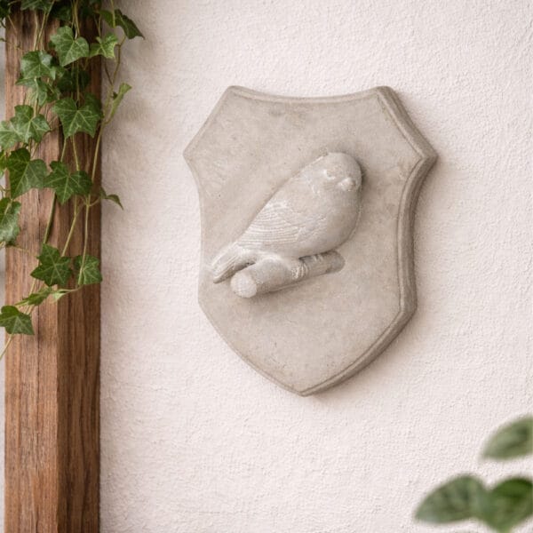 Väggdekoration i betong formad som en sköld med fågel i relief. Lugn och dekorativ detalj för väggen. Mått 18x13x6 cm.
