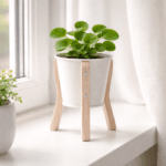 Vit blomkruka i plåt med träben i stilren design. Perfekt för små växter på fönsterbräda eller hylla. Diameter 13 cm, höjd 22 cm.