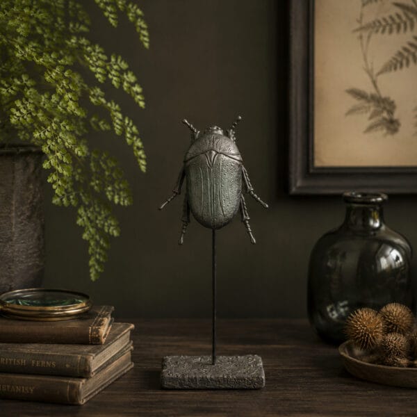Dekorativ skalbagge på ställning med grönskimrande metallfinish. Ett detaljrikt ornament som passar fint i botaniska och rustika miljöer.