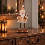 Tomte i trä, 22,5 cm hög, med gran och paket i händerna. En dekorativ julfigur i naturtoner för hyllan, byrån eller fönstret.