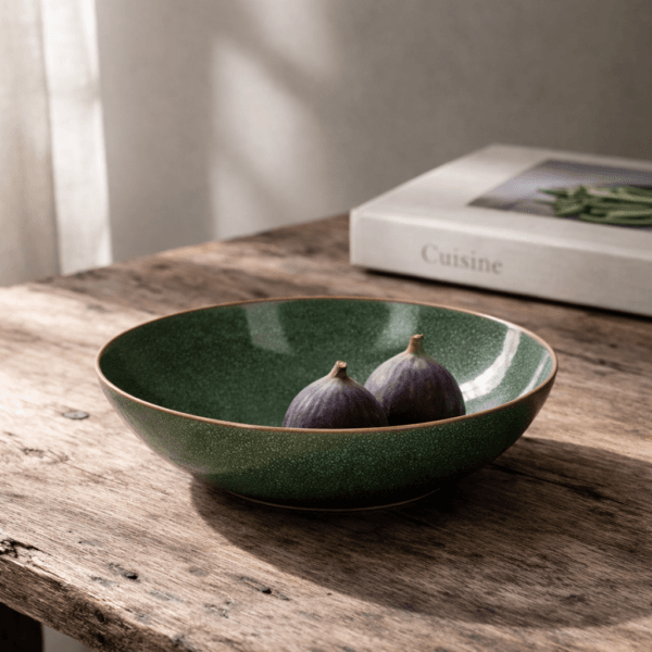 Keramikskål med grön glasyr och låg form. Stilren och dekorativ skål som passar perfekt för servering eller som detalj i köket.