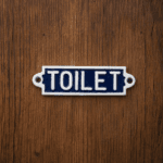 Skylt i gjutjärn med texten TOILET. En tydlig och dekorativ detalj för badrumsdörr eller gästtoalett med klassisk stil och hållbar känsla.