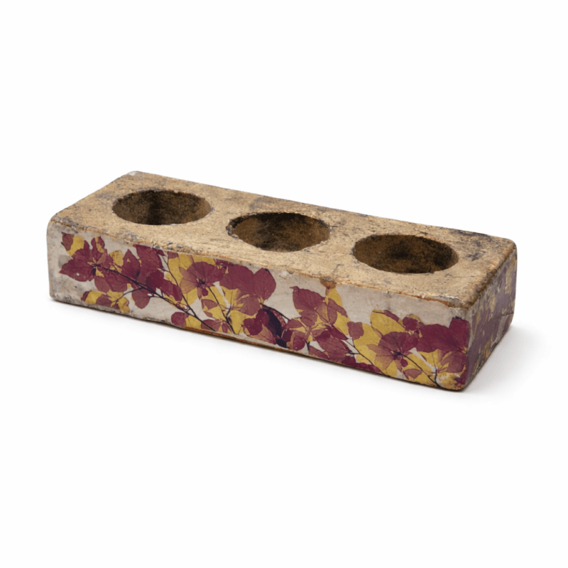 Värmeljushållare i betong med dekor av höstlöv i varma toner. Plats för tre ljus som ger ett mjukt sken. Mått 20×8×4 cm, passar fint i hemmets alla rum.