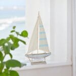 Dekorativ segelbåt i trä och textil i mjuka marina toner. Skapa en kustnära och harmonisk känsla i hemmet med maritim charm.