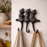 Dekorativ hängare i gjutjärn med tre katter. Praktiska krokar för nycklar, handdukar eller väskor. Passar perfekt i hall, kök eller lantlig miljö.