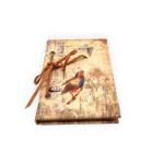 Anteckningsbok med hårt textilbeklätt omslag och en läderrem (går att knyta upp) som håller i pappret. Mått 10x15 cm.