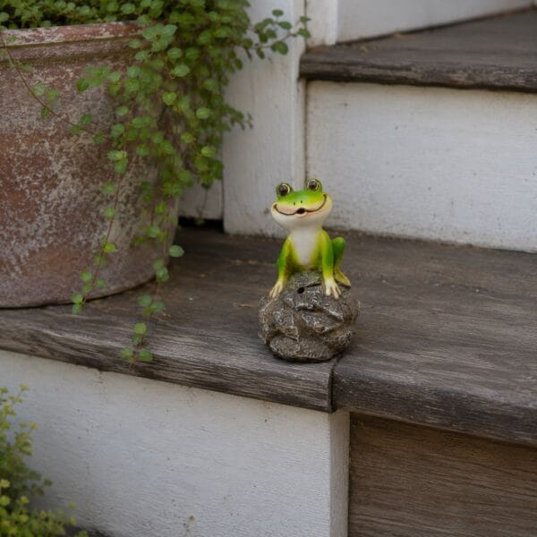 Charmig grodfigur i polyresin som gärna gör sig hörd när någon passerar. En dekorativ trädgårdsgäst som säger hej på sitt eget sätt.