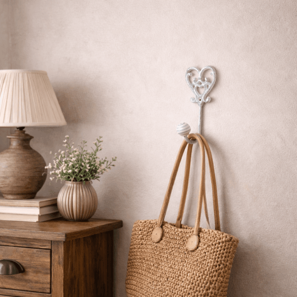 Dekorativ krok i vitmålat gjutjärn med romantiskt hjärtmotiv. Passar perfekt i sovrummet för upphängning av väskor, morgonrock eller andra småsaker.
