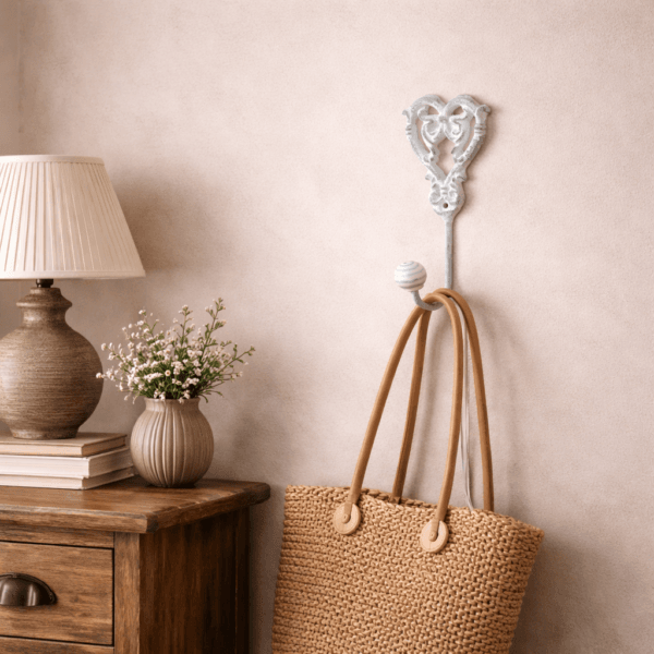 Dekorativ krok i vitmålat gjutjärn med romantiskt hjärtmotiv. Passar perfekt i sovrummet för upphängning av väskor, morgonrock eller andra småsaker.