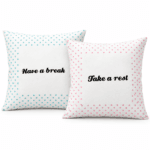 Två vita kuddfodral med rosa och turkosa prickar och svart text, 40×40 cm