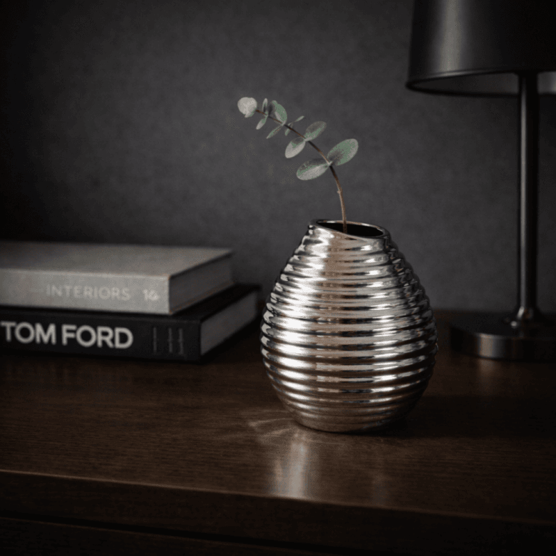 En dekorativ vas i keramik i en snygg silvermetallic nyans. Vasen har ett mönster och en form som ger den ett levande och unikt uttryck.