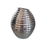 En dekorativ vas i keramik i en snygg silvermetallic nyans. Vasen har ett mönster och en form som ger den ett levande och unikt uttryck.