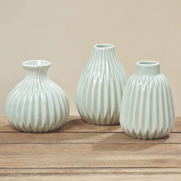 Tre dekorativa keramikvaser i grönt med räfflad yta och tre olika former. Perfekta för en liten kvist på hylla, bord eller i fönster. Höjd 5,5-9 cm.