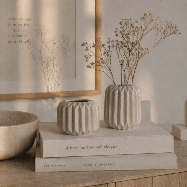 Två dekorativa keramikvaser i beige med räfflad yta och olika former. Perfekta för en liten kvist på hylla, bord eller i fönster. Höjd 5,5-9 cm.