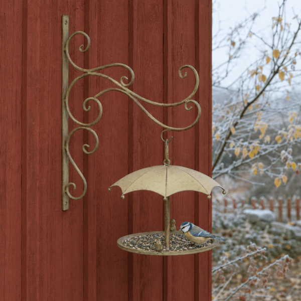 Väggmonterad fågelmatare i antikbehandlad metall med dekorativt paraply och avrinningshål.