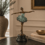 Elegant ballerina i brons med patinerad klänning och mörk sockel. En dekorativ skulptur som passar fint på bord, hylla eller byrå i hemmet.