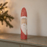 Snidad jultomte i bemålat trä på grågrön skänk i varm vintermiljö