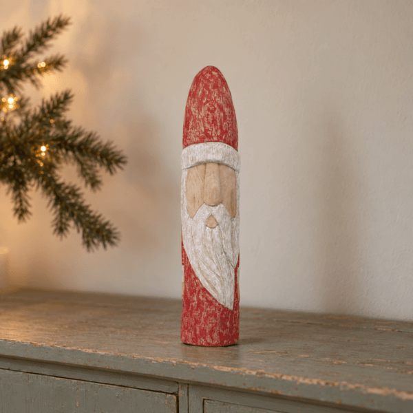 Snidad jultomte i bemålat trä på grågrön skänk i varm vintermiljö