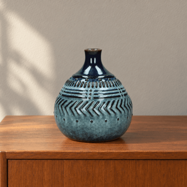 Blå keramikvas med reliefdekor på sideboard i 1950-/60-talsinspirerad miljö