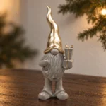 Tomte med guldmössa och paket i julmiljö 19 cm