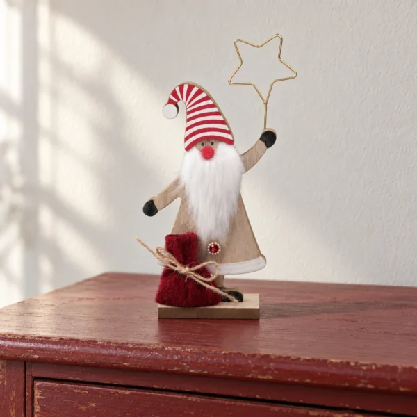 Tomte i trä med randig luva, vitt skägg, stjärna och röd säck på en dovt röd byrå.