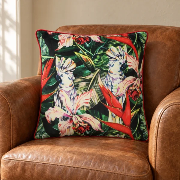 Tropic sammetskudde med kakaduor och tropiska blommor i en cognacsfärgad läderfåtölj