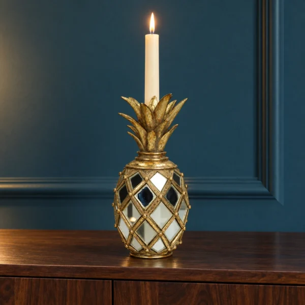 Guldfärgad ananasljusstake med spegelglas och tänt kronljus på en mörk valnötskonsol.